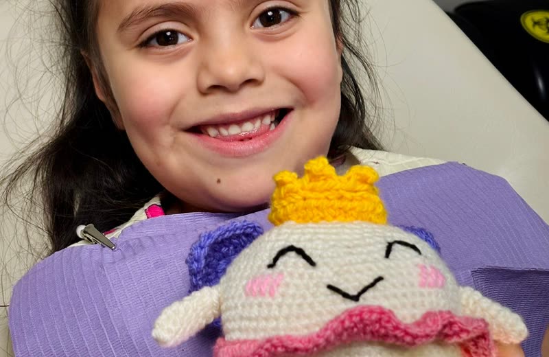 Niña sonriendo en el sillón dental de Especialidades Dentales Monterrey con su peluche Muelita, premio de su consulta de odontopediatría