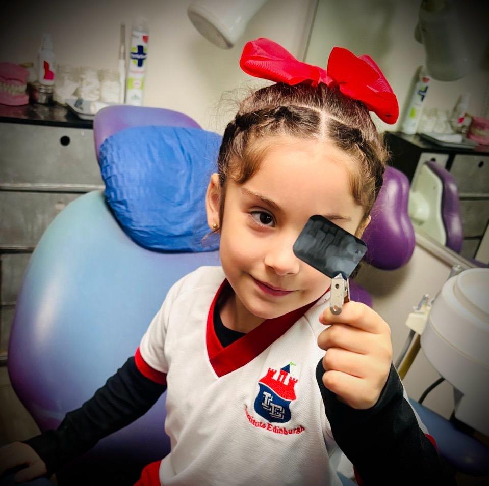 Niña con moño rojo disfrutando su visita al dentista en ambiente kid-friendly en Monterrey